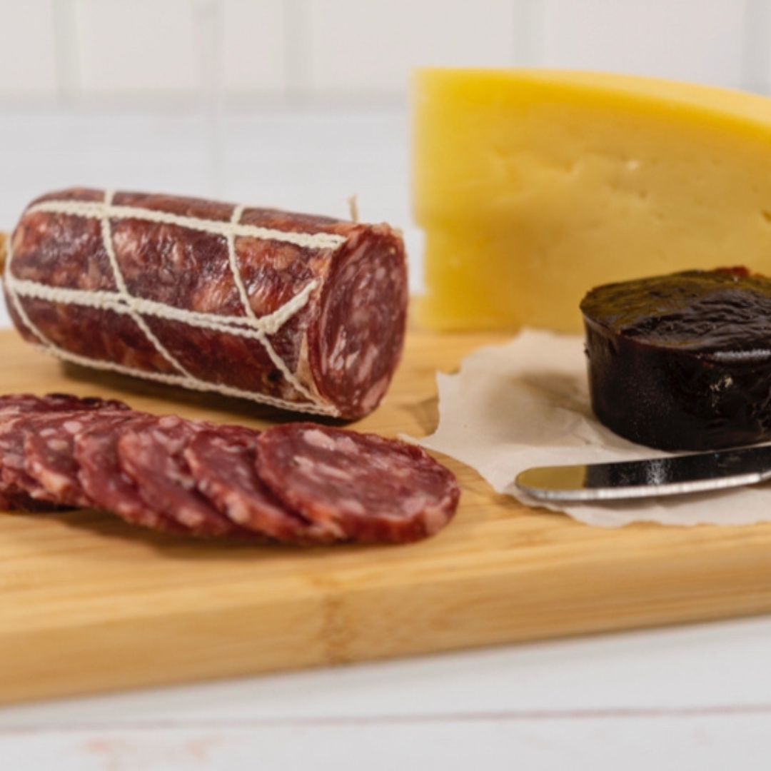 Truffle pork salami, thinly sliced on a wooden board, paired with quince paste and a block of cheddar cheese