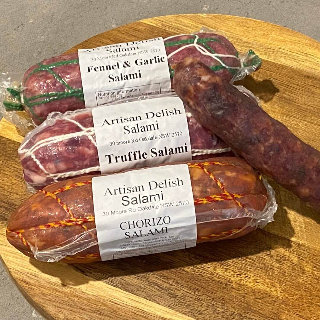 Trio of salami on a wooden board, fennel and garlic salami at the top, truffle salami in the middle and chorizo salami at the bottom