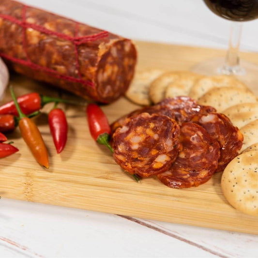 Calabrese Salami cut into thin slices on a charcuterie board served with crackers and red wine