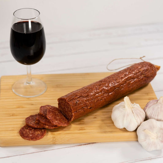 Hungarian Salami on a wooden board with garlic cloves and a glass of red wine